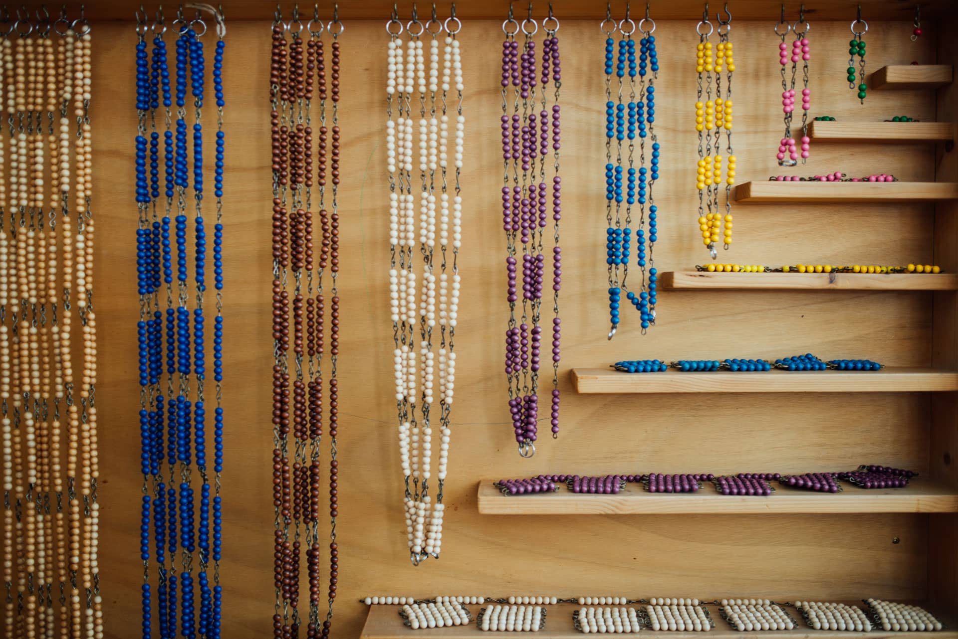 Colorful Montessori bead materials on wooden shelves