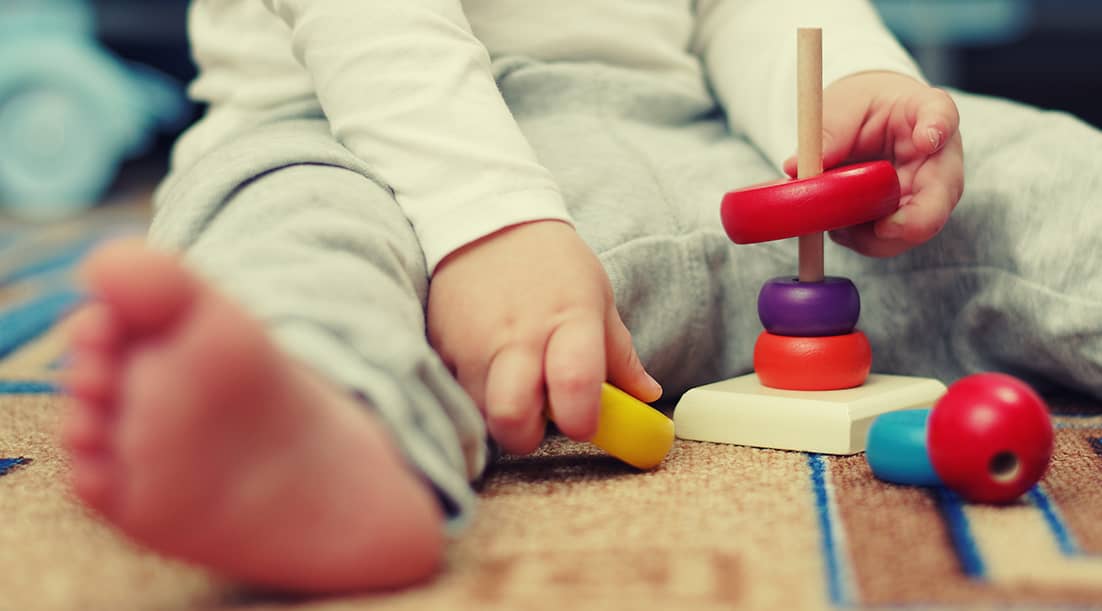 Infant exploring wooden toys at Academic North